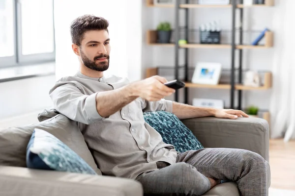 Homem com controle remoto assistindo TV em casa — Fotografia de Stock