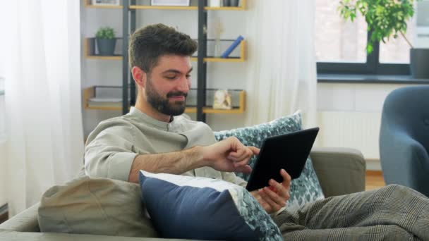 Χαμογελαστός άνθρωπος με tablet υπολογιστή στο σπίτι — Αρχείο Βίντεο