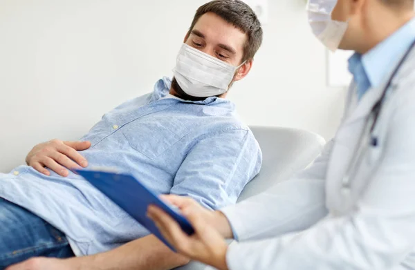 Médico do sexo masculino e paciente em máscaras no hospital — Fotografia de Stock