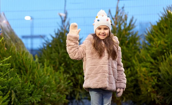 Little girl waving hand at christmas tree market — Stock Photo, Image