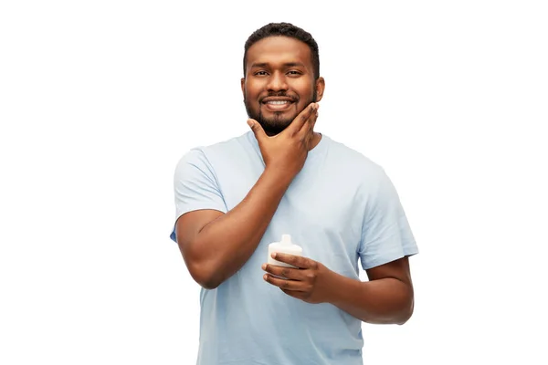 Homem africano feliz aplicando creme em seu rosto — Fotografia de Stock