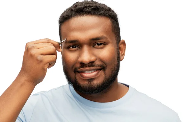 Homem africano com pinças pinça pinça sua sobrancelha — Fotografia de Stock