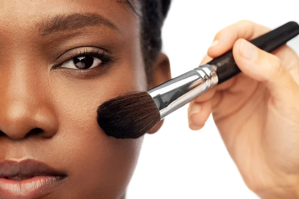 Visage de la femme africaine et la main avec brosse de maquillage — Photo