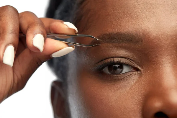 Afrikanerin mit Pinzette auf der Augenbraue — Stockfoto