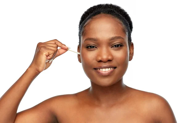 Glückliche Afrikanerin putzt Ohr mit Wattestäbchen — Stockfoto
