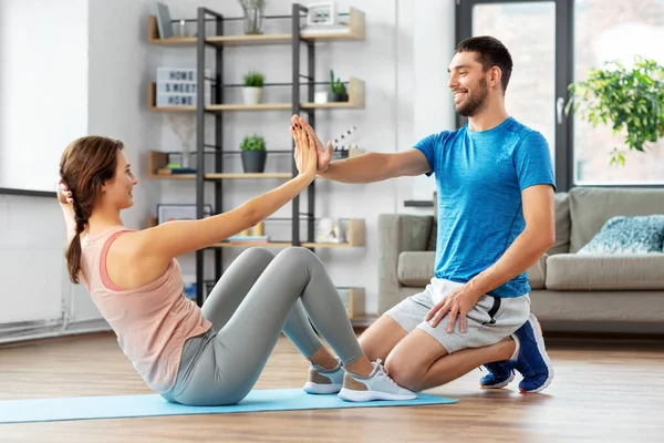 Mulher com personal trainer fazendo sit ups em casa — Fotografia de Stock