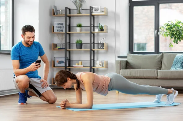 Mulher com personal trainer fazendo prancha em casa — Fotografia de Stock