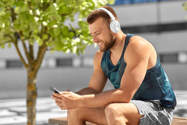 Joven atleta hombre con auriculares y teléfono inteligente —  Fotos de Stock