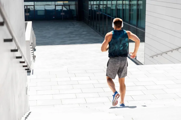 Young man in headphones running downstairs — Stock Photo, Image