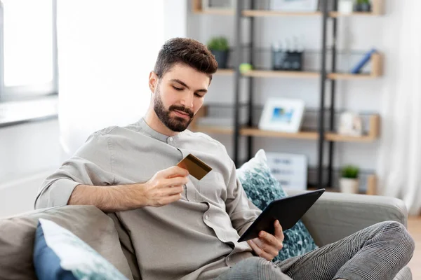 Homem com tablet computador e cartão de crédito em casa — Fotografia de Stock