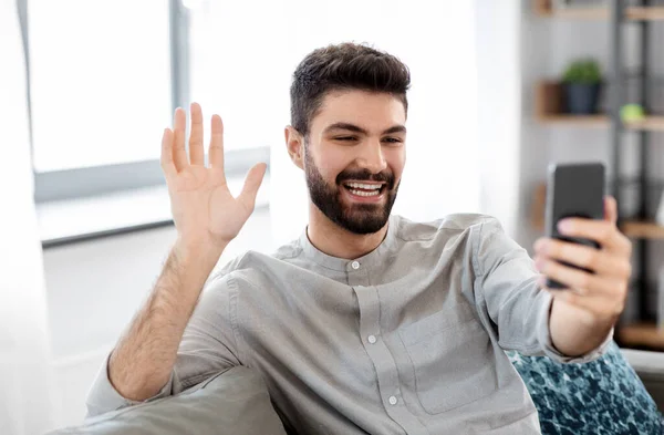 Hombre con teléfono inteligente que tiene videollamada en casa —  Fotos de Stock