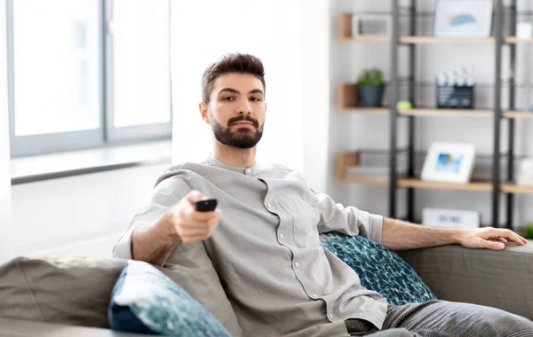 Homem com controle remoto assistindo TV em casa — Fotografia de Stock