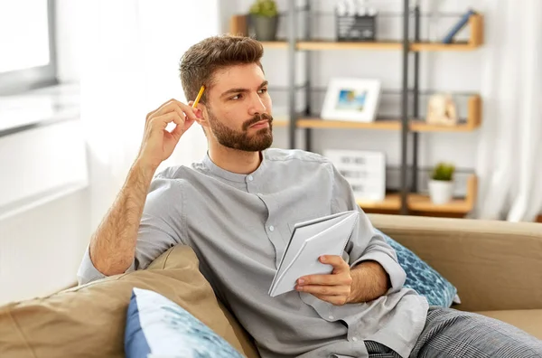 Man writing to notebook and thinking at home — Stock Photo, Image