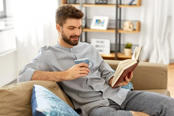 Homem lendo livro e beber café em casa — Fotografia de Stock