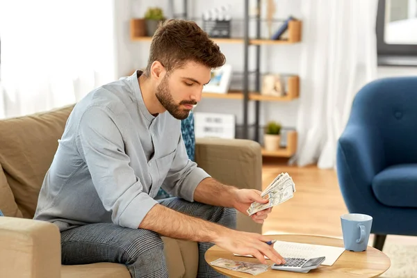 Man with money and calculator filling papers — Stock Photo, Image