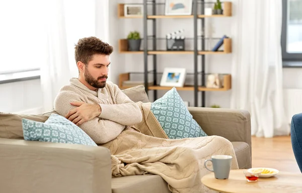 Zieke jongeman in deken met hete thee thuis — Stockfoto