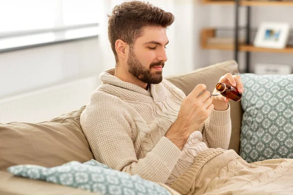 Uomo malato versando farmaci da bottiglia a cucchiaio — Foto Stock