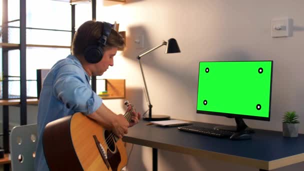 Homem em fones de ouvido tocando guitarra em casa — Vídeo de Stock