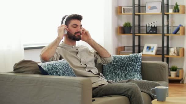 Kulaklıklı adam akıllı telefondan müzik dinliyor. — Stok video