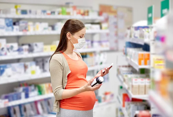 Mujer embarazada enmascarada con medicamentos en la farmacia — Foto de Stock