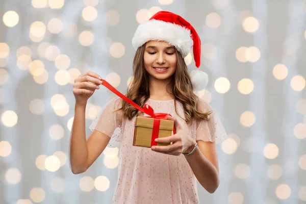 Έφηβος κορίτσι σε Σάντα καπέλο άνοιγμα χριστουγεννιάτικο δώρο — Φωτογραφία Αρχείου