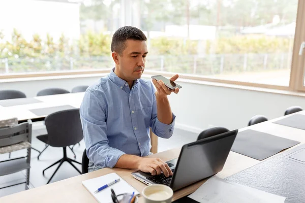 Hombre con teléfono inteligente y portátil en la oficina en casa — Foto de Stock