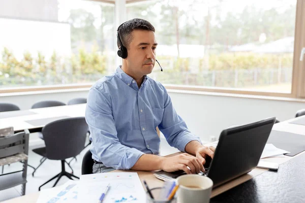 Hombre con auriculares y portátil trabajando en casa — Foto de Stock