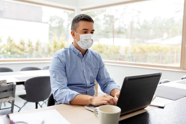 Hombre con máscara con el ordenador portátil de trabajo en casa oficina — Foto de Stock