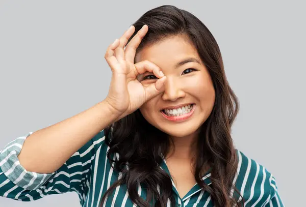 Souriant asiatique femme regarder à travers doigt lunettes Images De Stock Libres De Droits