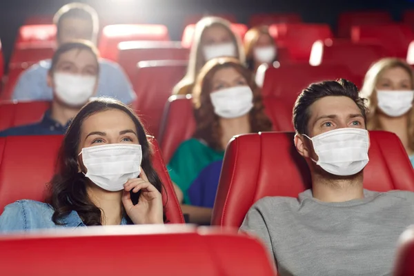 Люди в масках смотрят кино в кинотеатре — стоковое фото