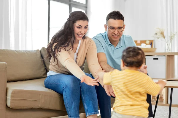 Família feliz com a criança sentada no sofá em casa — Fotografia de Stock