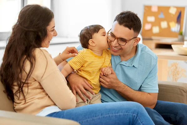 Familia feliz con el niño sentado en el sofá en casa —  Fotos de Stock