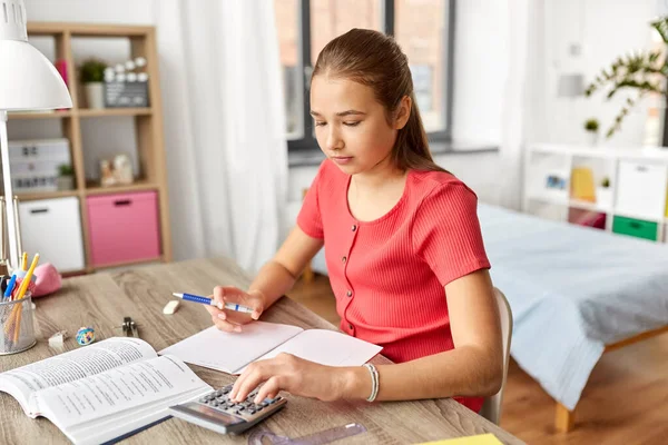 Estudante menina contando com calculadora em casa — Fotografia de Stock