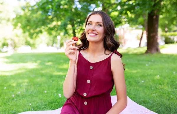 Mujer feliz comiendo fresa en el picnic en el parque —  Fotos de Stock