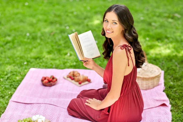 Szczęśliwa kobieta czytanie książki na pikniku w parku letnim — Zdjęcie stockowe