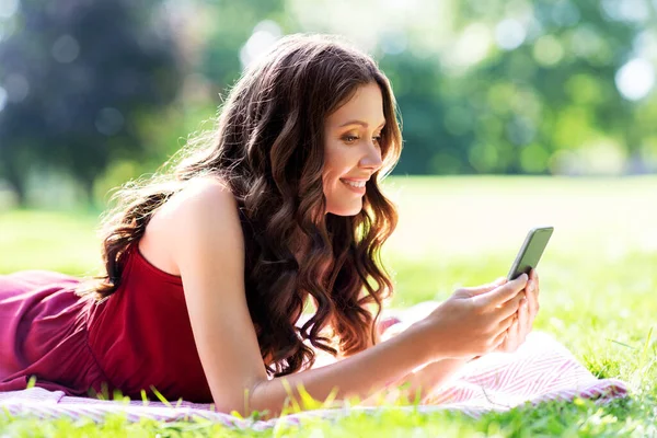 Šťastná žena s chytrým telefonem v parku — Stock fotografie