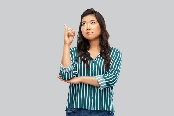 Asiatisk kvinna pekande finger upp på grå — Stockfoto