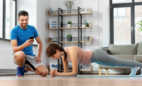 Vrouw met personal trainer doen plank thuis — Stockfoto