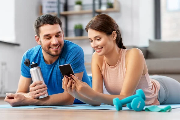Счастливая пара со смартфоном после занятий спортом дома — стоковое фото