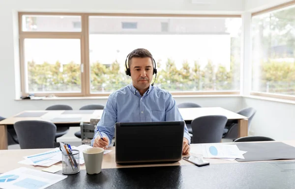 Man med headset och bärbar dator arbetar hemma — Stockfoto