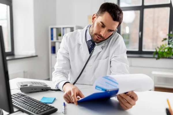 Arzt telefoniert am Schreibtisch im Krankenhaus — Stockfoto