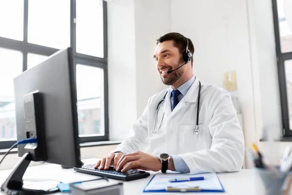 Zufriedener Arzt mit Computer und Headset im Krankenhaus — Stockfoto