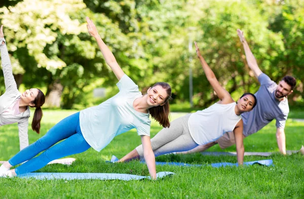 Group of people doing yoga at summer park — Stock Photo, Image