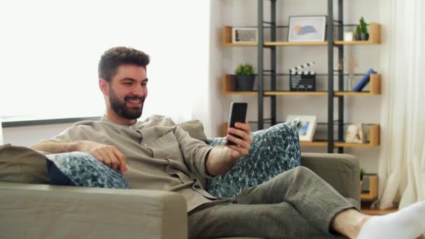 Hombre con teléfono inteligente que tiene videollamada en casa — Vídeos de Stock