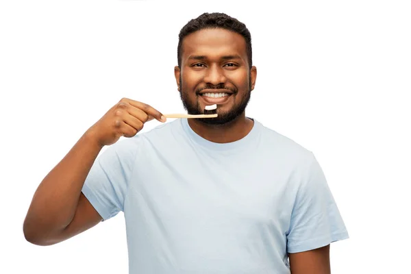 Улыбающийся африканский мужчина с чистящими зубы зубными щетками — стоковое фото