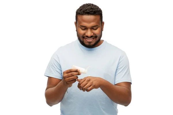 Homem africano feliz aplicando hidratante em sua mão — Fotografia de Stock