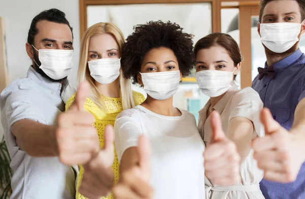 Personer i masker visar tummen upp på kontoret — Stockfoto