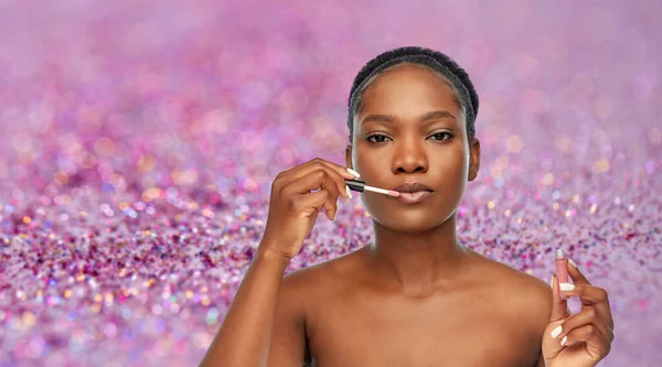 Mujer afroamericana aplicando brillo labial —  Fotos de Stock