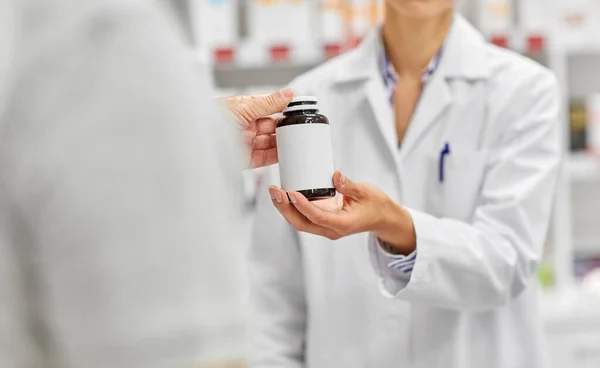 Фармацевт и клиент с лекарствами в аптеке — стоковое фото