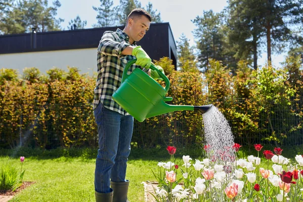 Мужчина средних лет поливает цветы в саду — стоковое фото